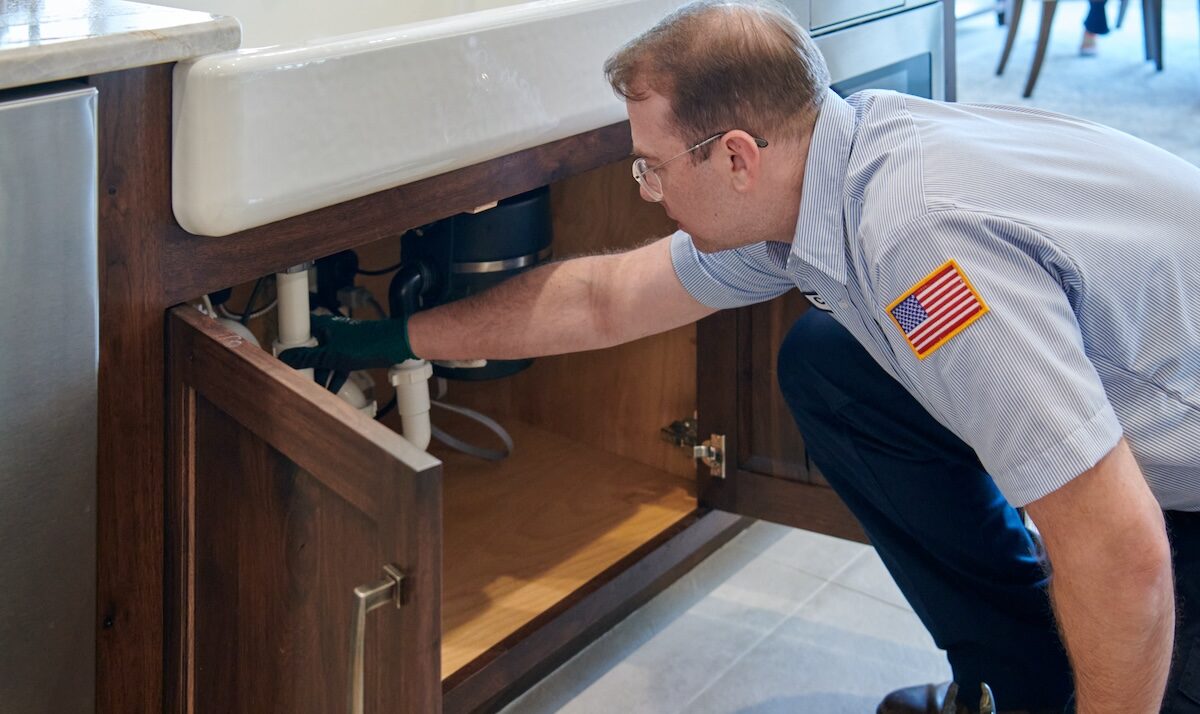 technician inspecting draining below sink