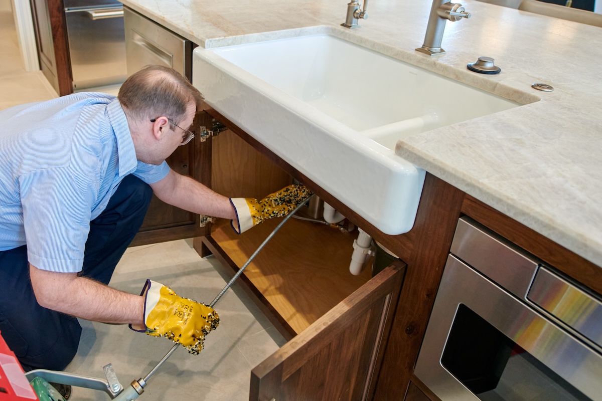 technician inspecting kitchen drain below sink