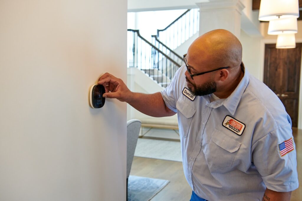 hvac technician looking at thermostat